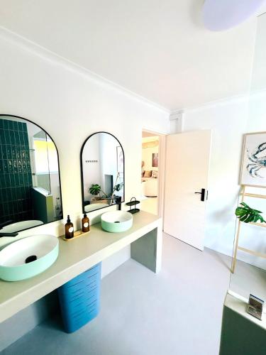 a bathroom with two sinks and two mirrors at House Charisma in Britannia Bay