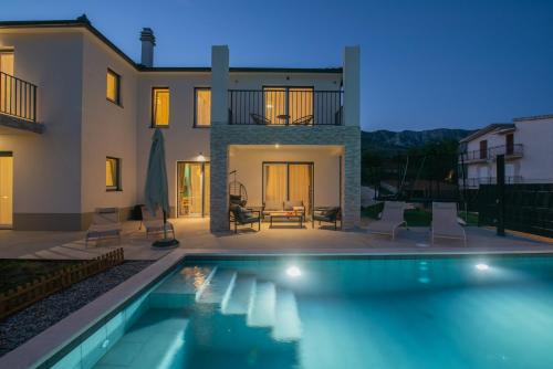 a villa with a swimming pool in front of a house at Villa Ginger Modern Villa with Private Pool in Omiš