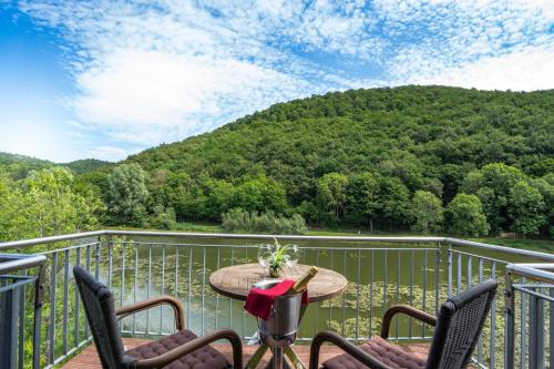 a balcony with a table and chairs and a mountain at Hotel-Restaurant Eifeler Seehütte in Rieden