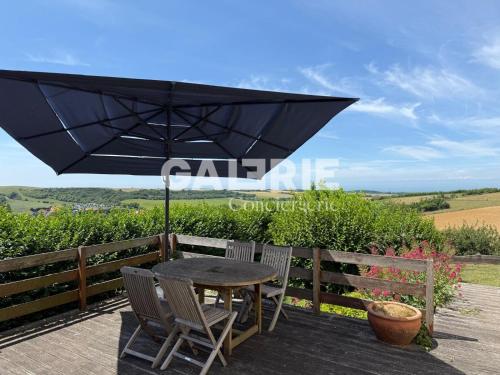 a table and chairs under an umbrella on a deck at GC - Villa L'Idéal - Vue Mer in Hervelinghen