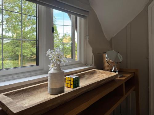 a vase of flowers on a counter next to a window at 3 Bedrooms, 3 Double Beds, 6 Guests, Countryside Thatched Cottage in Four Marks