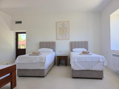a bedroom with two beds and a table in it at Imanje Dorf in Ravno Selo
