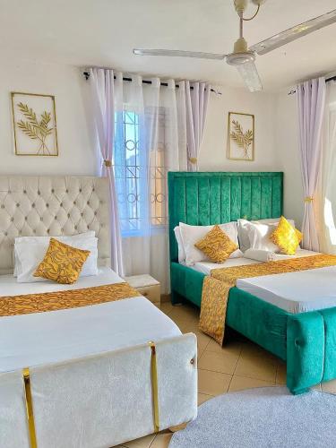 a bedroom with two beds and a green headboard at tabby stays one bedroom with two beds bamburi in Mombasa