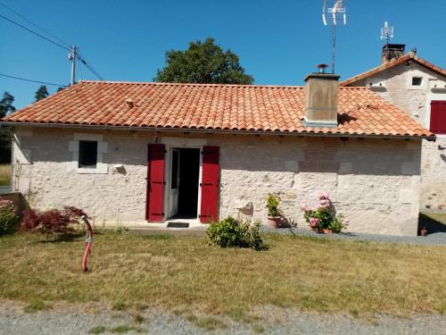 a white stone house with red doors and a yard at petite maison Bellevue in La Celle-sous-Gouzon