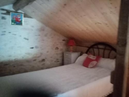 a small bedroom with a bed with a red pillow at petite maison Bellevue in La Celle-sous-Gouzon