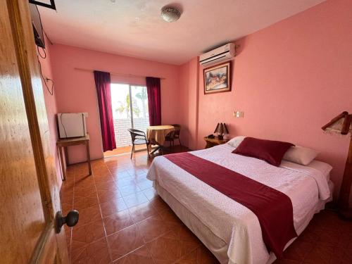 a bedroom with a bed and a table and a window at Hotel Barbasquillo in Manta