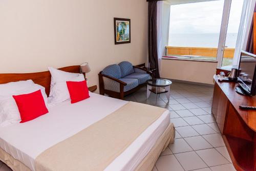 a hotel room with a bed and a chair and a window at Hôtel des Roches Kourou in Kourou