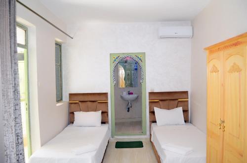 two beds in a room with a mirror and a sink at Riad Dar Lokman in Marrakesh