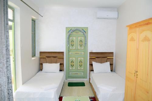 two beds in a room with a green door at Riad Dar Lokman in Marrakesh