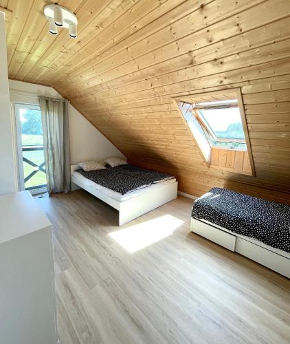 two beds in a room with a wooden ceiling at Brajnickie Zacisze in Brajniki