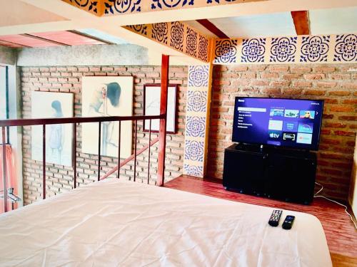 a bedroom with a bed and a tv and a brick wall at Mar en Casa - Taganga - Vista al Mar in Taganga