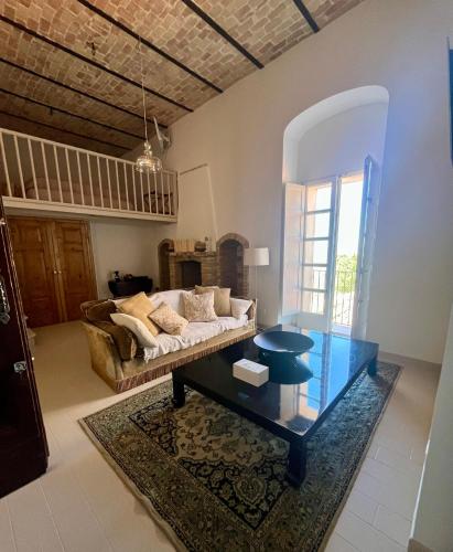 a living room with a couch and a glass table at Dimora Palazzo De Luca - Intra Alborgodiffuso - Loft di Charme del 700 con Vasca doppia e Camino in Serracapriola