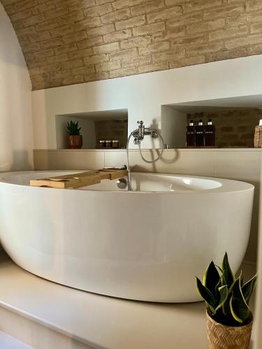 a white tub in a bathroom with a sink at Dimora Palazzo De Luca - Intra Alborgodiffuso - Loft di Charme del 700 con Vasca doppia e Camino in Serracapriola