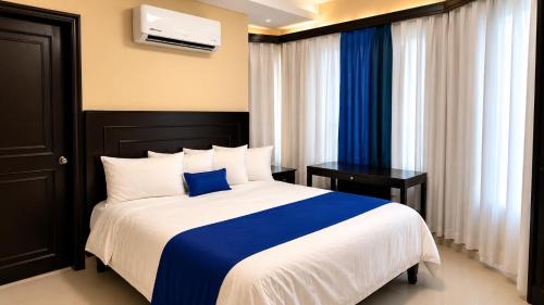 a bedroom with a bed with a blue and white blanket at Hotel Aljófar in Montemorelos