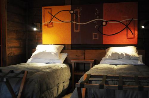 a bedroom with two beds and a painting on the wall at Las Pitras Lodge in Epuyén