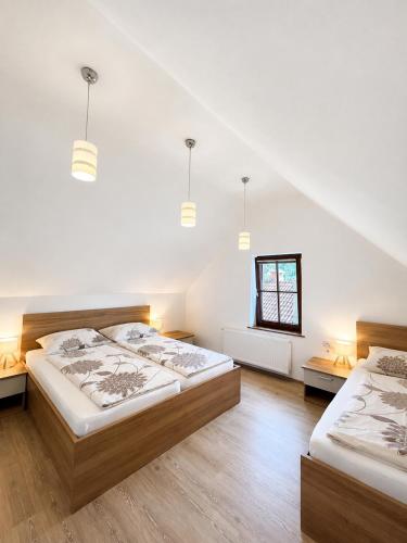 two beds in a room with white walls and wooden floors at Apartmaji Kramar Rateče in Kranjska Gora