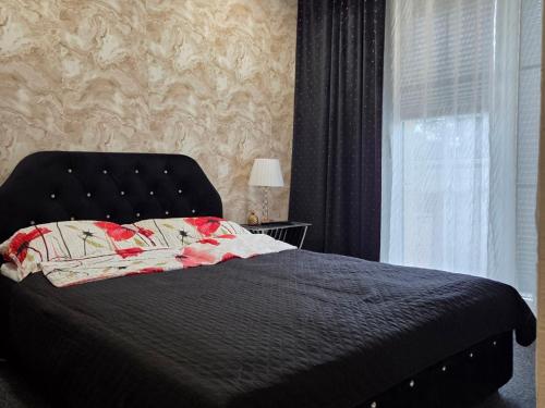 a bedroom with a bed with a black headboard and a window at Apartament Glamour in Rybnik