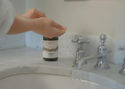 a person reaching for a bottle of wine on a sink at Comrie Old Schoolhouse in Comrie