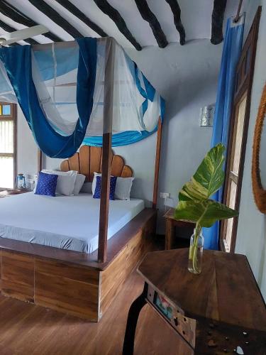 a bedroom with a canopy bed and a table at Serene Apartments in Kinyasini