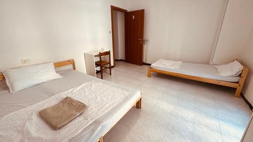 ein Schlafzimmer mit zwei Betten, einem Tisch und einer Tür in der Unterkunft Double and Triple Rooms near Principe Station Shared Bathroom in Genua