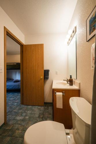 a bathroom with a toilet and a sink and a bed at Grayling Getaway, Cabin 1 at Lower Kenai Lodge in Kenai
