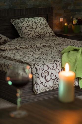 a bed with a candle and a glass of wine at Family Hotel BOHEMA in Ognyanovo