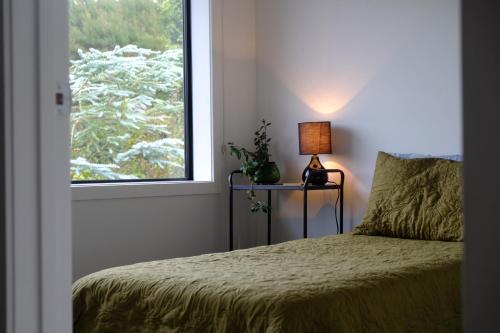 a bedroom with a bed with a lamp and a window at Bordeaux Retreat in Te Kauwhata