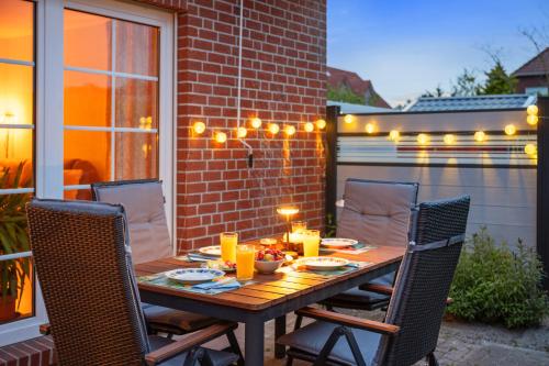 a wooden table with chairs on a patio with lights at Zaunkönigin in Norden