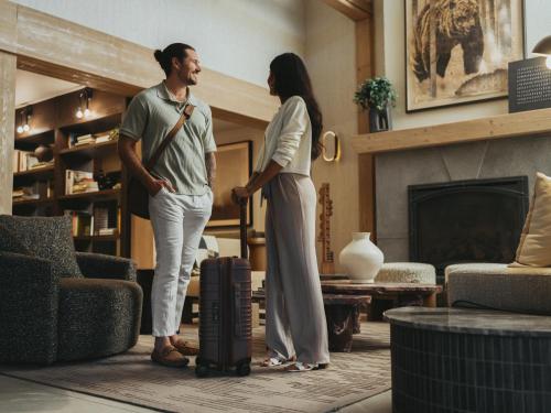 Ein Mann und eine Frau stehen mit einem Koffer in einem Wohnzimmer. in der Unterkunft The Kenrick Hotel in Banff