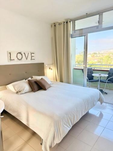 a bedroom with a bed with a love sign on the wall at Edificio Las Marañuelas, Puerto La Cruz, Islas Canarias Tenerife in Puerto de la Cruz