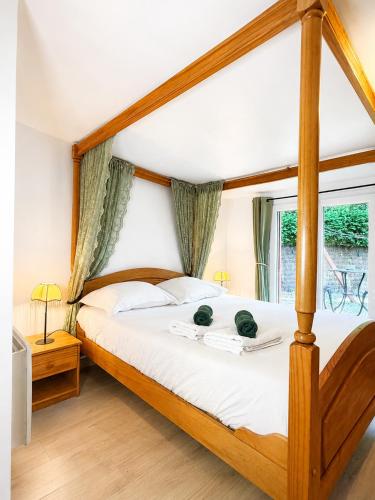 a bedroom with a wooden canopy bed with a window at Chalet Forestôchat in Tressé
