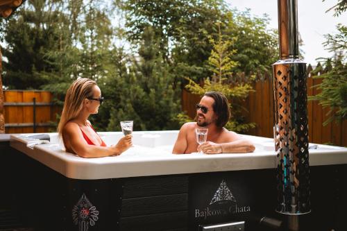 two people sitting in a bathtub with glasses of champagne at Bajkowa LUX Magiczne Domki z Jacuzzi in Murzasichle