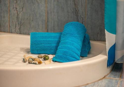 a bathroom with blue towels and shells in a tub at Studios Vagelis in Kalamitsi