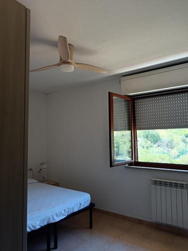 a bedroom with a ceiling fan and a window at Casa al Pozzarello in Porto Santo Stefano