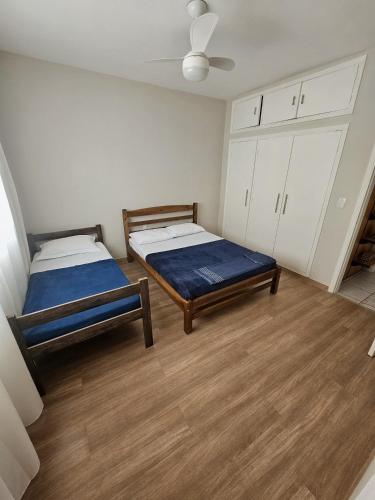 two beds in a room with wooden floors and white cabinets at Hotel Deck Taquaral in Campinas
