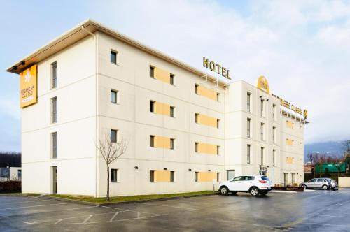 a white hotel with a car parked in a parking lot at Première Classe Annemasse Ville La Grand in Ville-la-Grand
