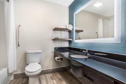 a bathroom with a toilet and a sink with a mirror at Best Western Niceville-Destin in Niceville