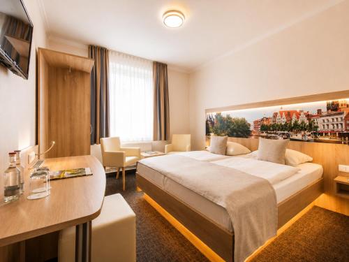 a hotel room with a large bed and a desk at Hotel Jensen in Lübeck