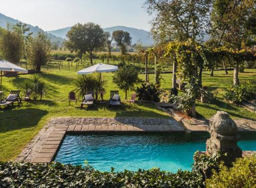 a pool in a yard with chairs and umbrellas at 1720 Quinta da Cancela - Winery & Farmhouse in Guimarães
