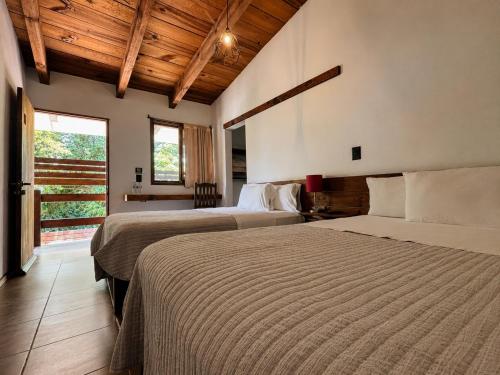 two beds in a room with wooden ceilings at Meson de Valle Hotel in Valle de Bravo