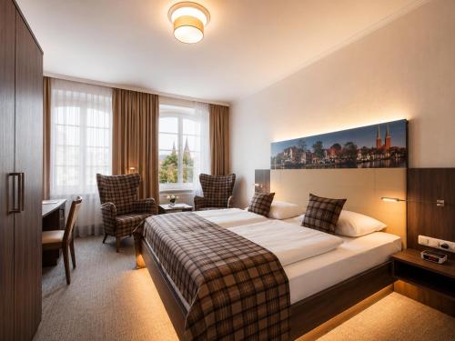 a hotel room with a bed and a table and chairs at Hotel Jensen in Lübeck