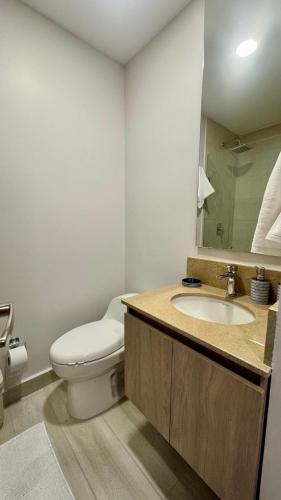 a bathroom with a toilet and a sink with a mirror at Apartaestudio tipo loft cerca al mar in Santa Marta