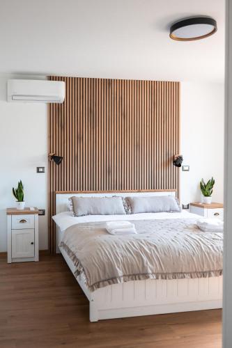 a bedroom with a white bed with a wooden headboard at I&R Apartma in Hrpelje