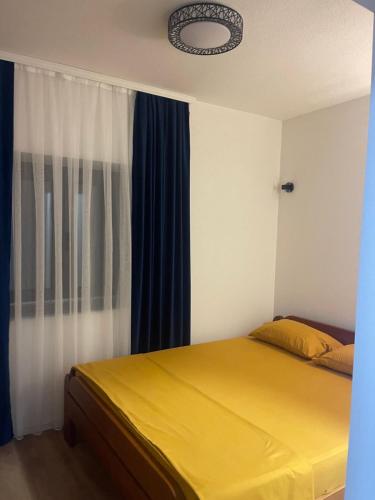 a bedroom with a yellow bed and blue curtains at Guest House Vuthaj in Vusanje