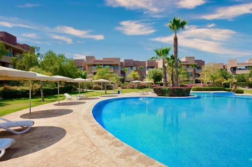 a swimming pool in a resort with chairs and umbrellas at Marrakech Golf Luxury in Marrakesh