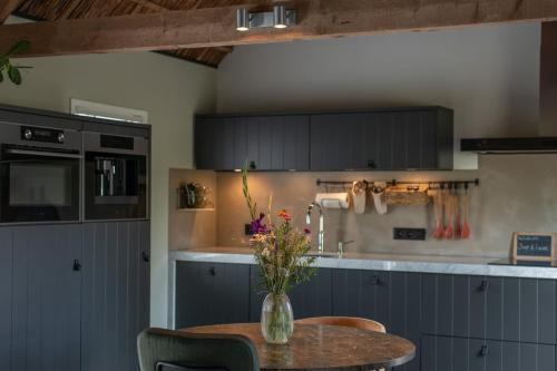 a kitchen with a table with a vase of flowers on it at Gastenverblijf Begheynhof - your perfect escape in Biervliet