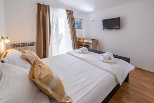 a bedroom with two beds and a tv on the wall at Apartments Marin in Podstrana