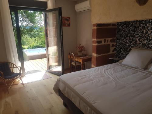a bedroom with a bed and a sliding glass door at Maison d'hôtes en grès rouge in Lanteuil
