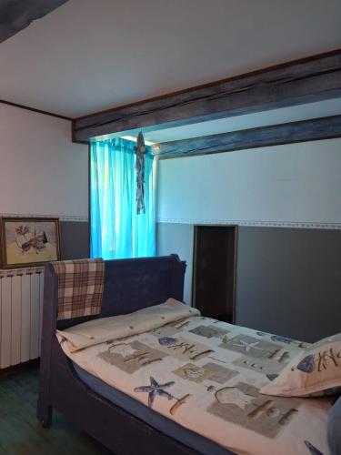 a bedroom with a bed with a blue curtain and a window at Le mas des Anglades in Saint-André-de-Valborgne