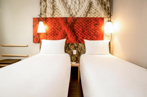 two beds in a room with a painting on the wall at Ibis Toulouse Purpan Aeroport in Toulouse